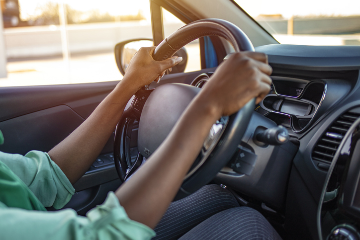 Image of a woman's hands on a automobile steering wheel.
